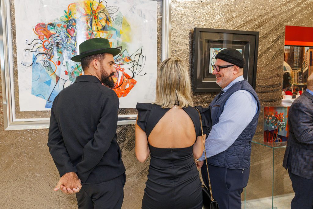 Yoel Benharrouche and guests viewing artwork at the exhibition