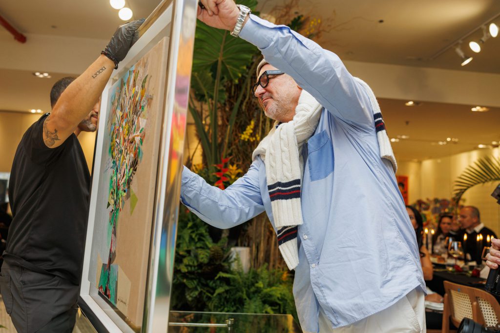 Yoel Benharrouche presenting a framed artwork